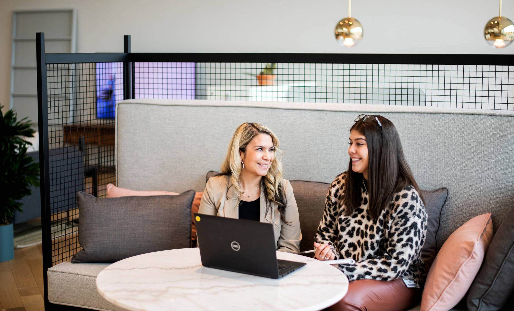 Two women talking with a laptop open in front of them
